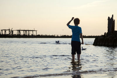 Rear view of man standing in sea against sky