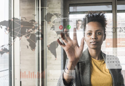 Young woman receiving a call on glass wall with world map in office