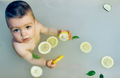 Portrait of cute smiling boy sitting in bathtub
