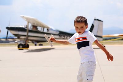Cute boy with toy airplane at runway during sunny day