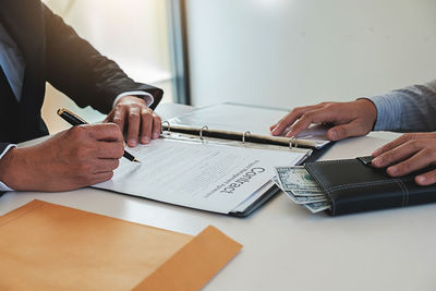 Midsection of man holding paper at table