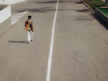 Rear view of woman walking on road