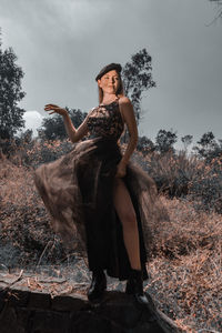 Woman standing by tree against sky