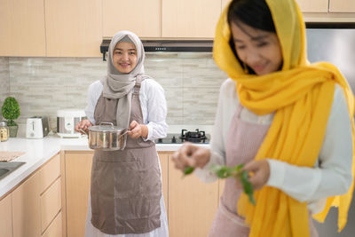 Woman holding food while standing at kitchen