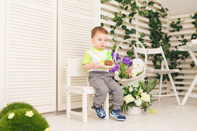 Full length of cute boy sitting on potted plant