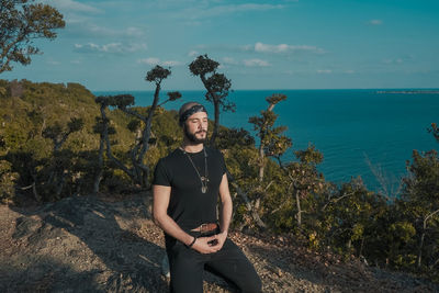 Full length of man meditating while kneeling in forest against sky