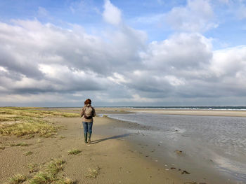 Rear view of woman on beach against sky