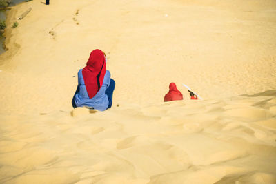 Rear view of woman sitting on sand at beach