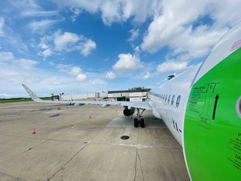 Airplane on airport runway against sky