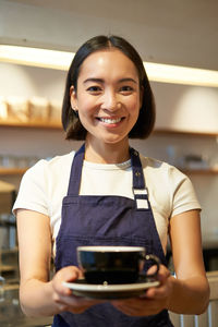 Portrait of smiling young woman standing at home