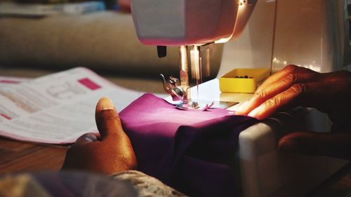 Cropped hands of tailor stitching textile on sewing machine