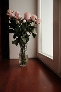 Flower vase on table by window at home