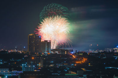 Firework display over illuminated buildings in city at night