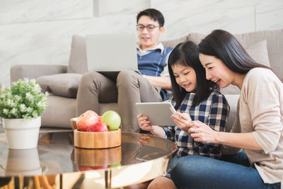 Young woman using mobile phone while sitting on sofa