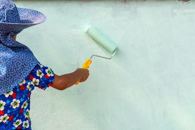 Low section of woman holding paper against wall at home