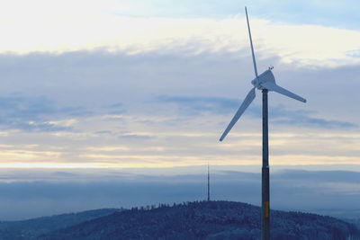 Wind turbines on landscape against sky during sunset