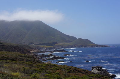 Scenic view of sea and mountains against blue sky
