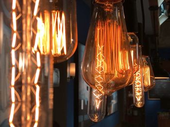 Close-up of illuminated light bulbs hanging at night