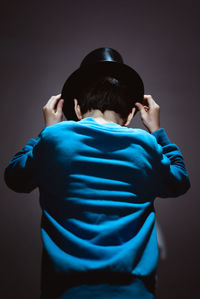 Rear view of boy wearing hat while standing against gray background