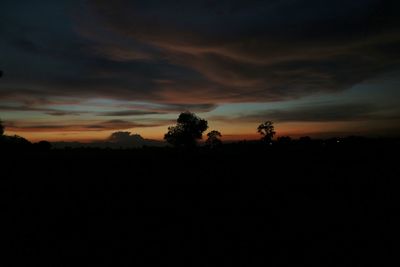 Silhouette trees against dramatic sky during sunset
