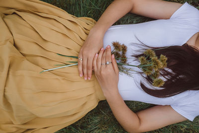 Midsection of woman with flowers lying on field