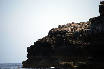 Rock formations by sea against clear sky