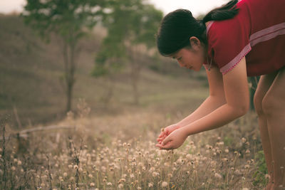 Young woman touching wild flowers on filed