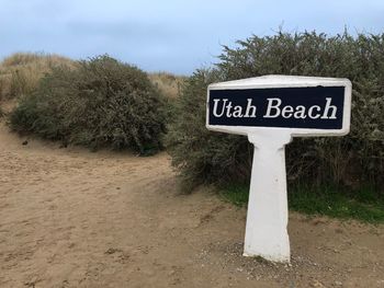 Information sign on road by trees against sky