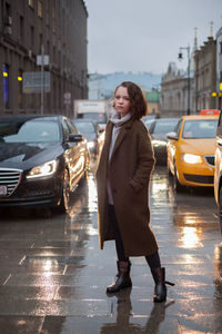 Portrait of woman standing on wet road in city