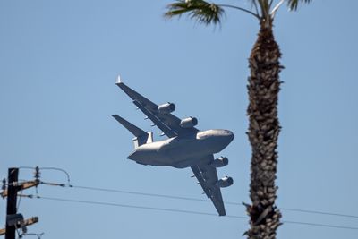 Low angle view of airplane flying against clear blue sky