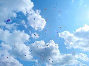 Low angle view of balloons flying against blue sky