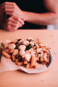 Close-up of hand holding bread in plate on table