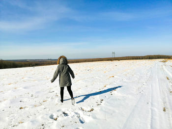 Rear view of man walking on snow covered land