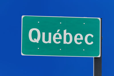 Low angle view of road sign against blue background