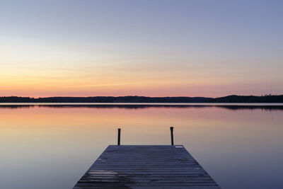 Pier over lake against sky during sunset