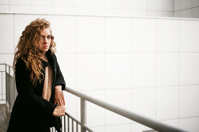 Portrait of woman standing against wall