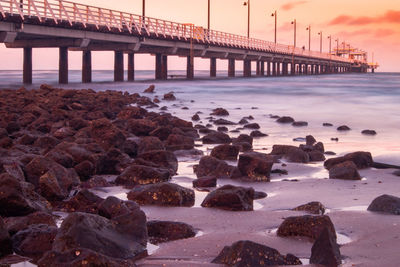 Bridge over sea against sky during sunset