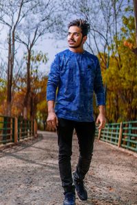 Full length of young man standing on footpath