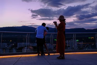 Rear view of man photographing against sky during sunset