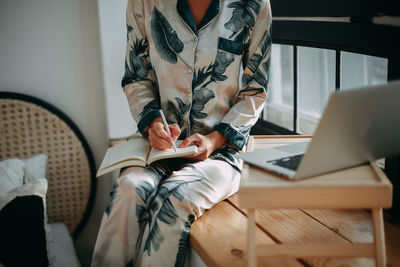 Midsection of woman sitting on sofa at home