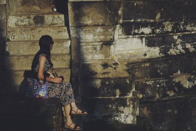 Side view of woman standing against building