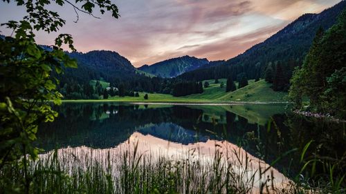 Scenic view of lake and mountains against sky at sunset