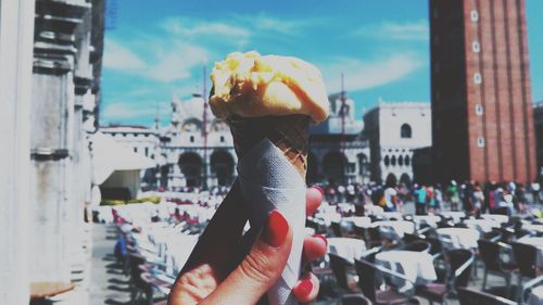 Cropped hand of woman holding ice cream cone against saint mark basilica