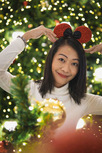 Portrait of young woman holding christmas tree