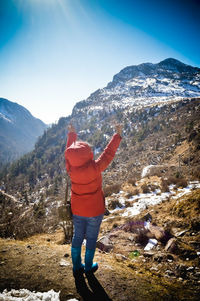 Rear view of woman standing on mountain against sky