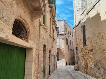 Alley amidst buildings in town against sky