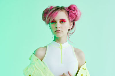 Portrait of young woman standing against blue background