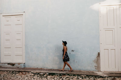 Rear view of woman standing against white wall