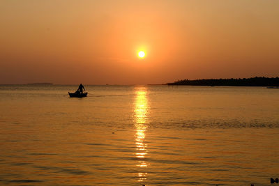 Scenic view of two people on boat with sunset over sea