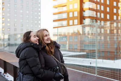 Smiling female couple looking at modern apartment buildings